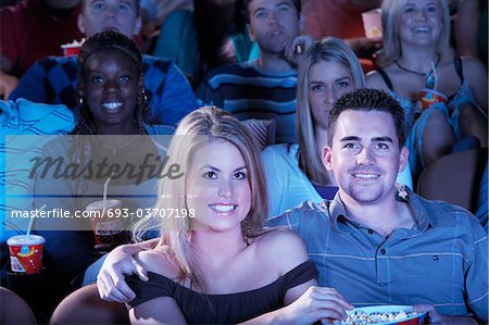 Jeune couple assis, les bras autour, regarder film dans le théâtre