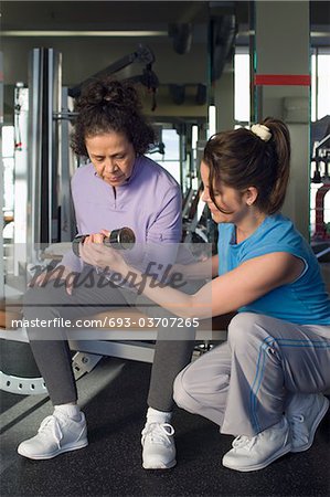 Trainer Assisting Senior Woman in Weightlifting With Dumbbell