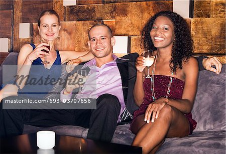 Man with two women sitting on couch in bar