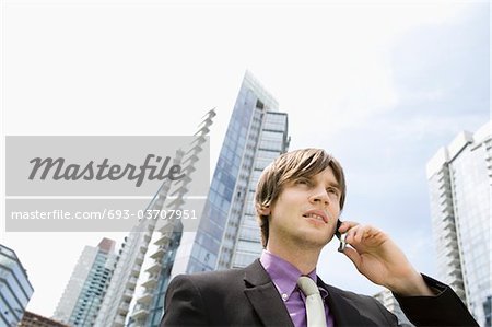 Business man using mobile phone, outside office buildings