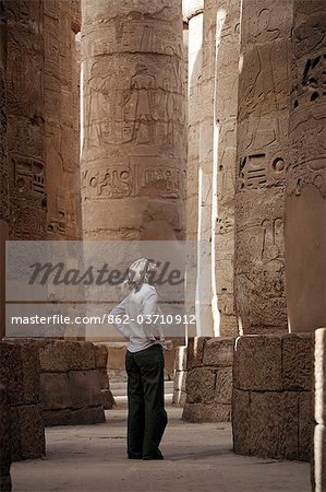 Egypte, Karnak. Un touriste se penche vers le haut les colonnes en pierre massives dans la grande salle hypostyle.