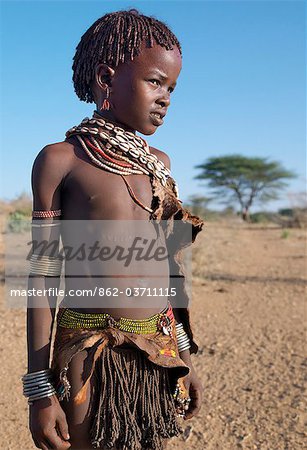 A Hamar girl in traditional attire. Her leather skirt is made from the twisted strands of goatskin. Cowries are always popular to embellish a woman's or girl's appearance.The Hamar are semi-nomadic pastoralists who live in harsh country around the Hamar Mountains of Southwest Ethiopia.