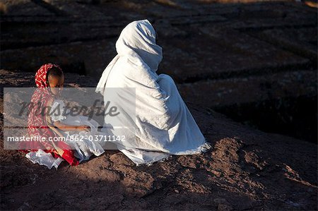 Äthiopien, Lalibela. Eine Frau betet von Bet Giyorgis, während ihre Tochter Konzentration verliert.