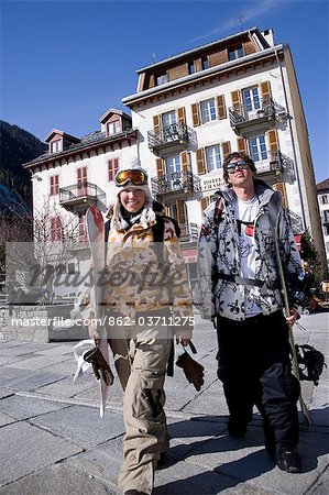 A couple in snowboarding gear walk through Chamonix,France