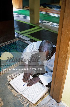 Ghana,Northern region,Tamale. A Muslim prays and reads the Quran at a Mosque in Tamale during Ramadan.