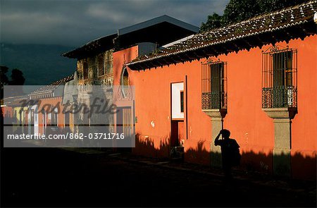 Un homme marche le long de l'une rue dans le centre-ville de Antigua à côté des maisons peintes de couleurs vives.