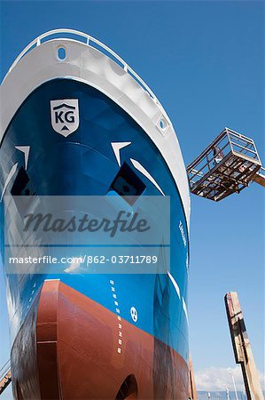 Iceland,in Reykjavik. the countries capital,port area a modern fishing vessel is repainted as it is hauled out of the water into a large slipway,the worker gaining access to the side of the ship via a rather ancient truck based crane.