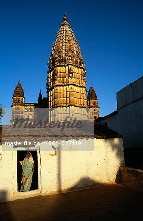 A local woman emerges from her home behind which soars the striking outline of the Chaturbuj Mandir,or temple.