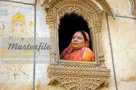 Inde, Rajasthan, Jaiselmer, Patwon ki Haveli. Lady habillée traditionnellement habillée ressemble d'une des fenêtres lourdement décorés dans celui en mieux Havelis préservé de la ville.