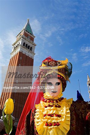 Personnes de carnaval de Venise en Costumes et masques avec clocher derrière