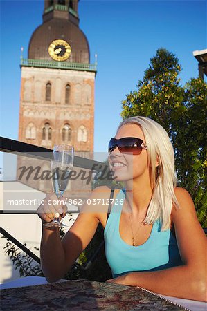 Woman drinking champagne on rooftop restaurant in Hotel Gutenbergs with Dome Cathedral in background, Riga, Latvi.