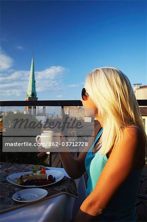 Kaffeetrinken am Restaurant auf der Dachterrasse im Hotel Gutenbergs mit St Jacobs Kathedrale im Hintergrund, Riga, Latvi Frau.