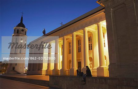 Lithuania, Vilnius, Women Sitting Outside Vilnius Cathedral And Bell Tower At Dusk
