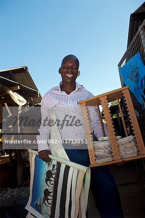 Malawi, Zomba. In the market, a smiling  Entrepreneur walks around the market selling his African artwork