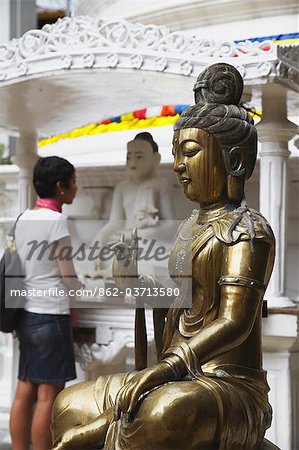 Woman visiting Gangaramaya temple, Cinnamon Gardens, Colombo, Sri Lank.