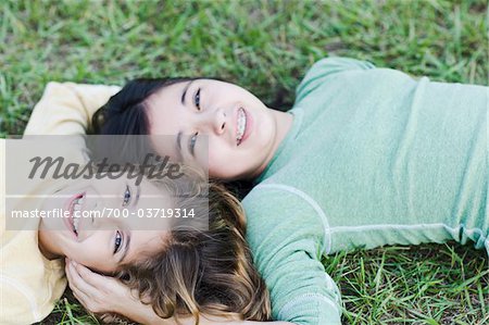 Schwestern, die zusammen auf Gras liegend