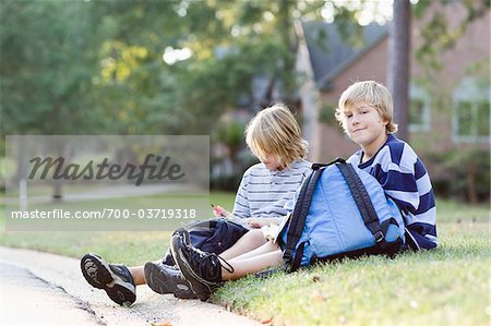 Garçons assis sur l'herbe avec sacs à dos