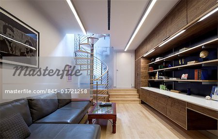 Moderne salon décloisonné avec escalier en colimaçon, unité de canapé et de stockage et bureau. Architectes : Nous Design - Winston Ely