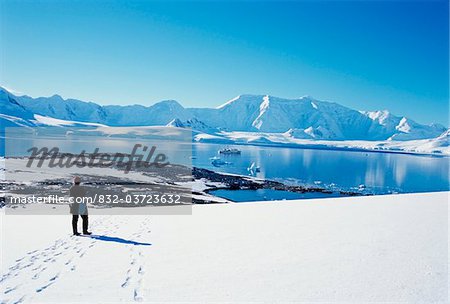 Tourist in snow overlooking landscape of Wiencke Island