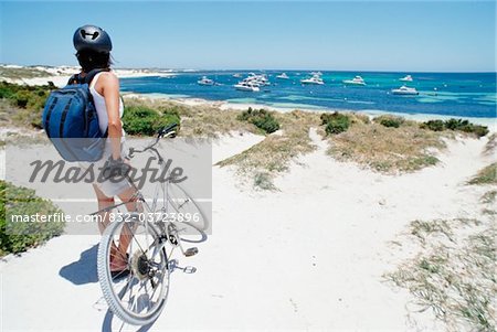 Femelle touristique permanent avec le vélo sur la plage