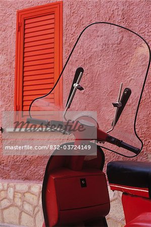 Red scooter against a pink wall, close up