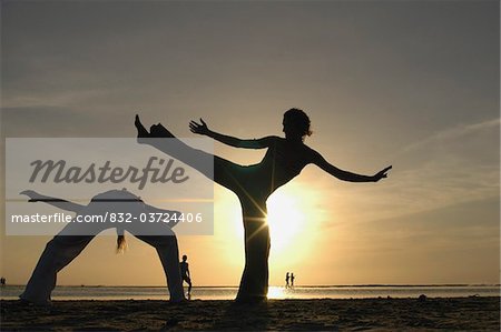 Zwei Frauen silhouetted tun Capoeira am Strand bei Sonnenuntergang