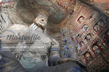 Statue and carvings in ancient Buddhist temple grotto.