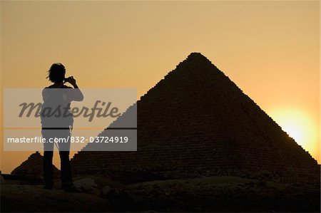 Silhouette de femme photographier les pyramides au crépuscule