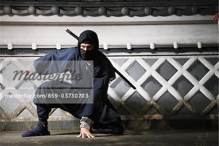 Maskierter Ninja hockend von Mauer