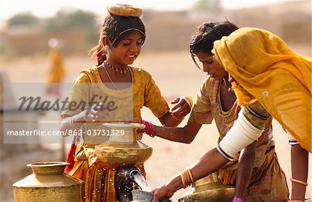 Tribal women and girls collecting water from a well in the desert near Jaisalmer, State of Rajasthan, India