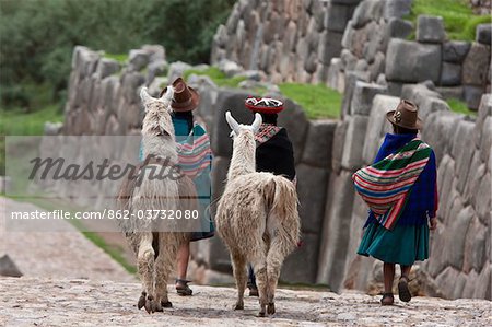 Peru, Native Indian women lead their llamas past the ruins of Saqsaywaman, built by the Incas on pre-Inca foundations.