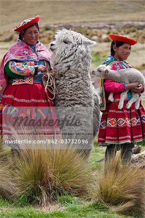 Peru, Females with an alpaca and lamb at Abra La Raya, the highest point (4318m) on the  Andean Explorer  express train (Cusco-Puno)