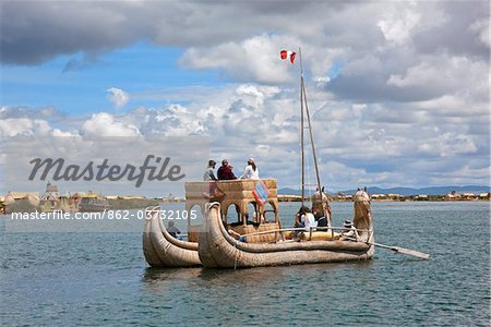 Peru, A large reed boat used by tourists is rowed down the main channel between the unique floating islands of Uros on Lake Titicaca.