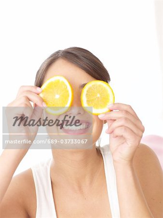 Woman holding orange slices in front of her face