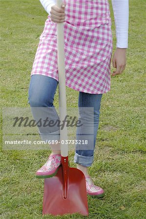 Woman in garden resting foot on shovel