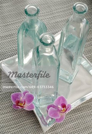 Orchid blossoms and bottles of water Orchid blossoms and bottles of water