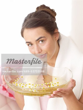 Woman holding bowl with camomile petals