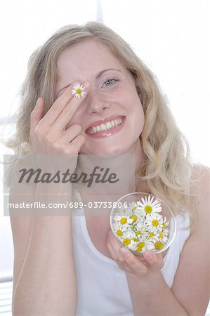 Woman holding bowl with marguerite blossoms