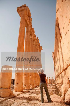 Syria, Palmyra. A tourist stands beneath the towering columns of the Bel Temple.