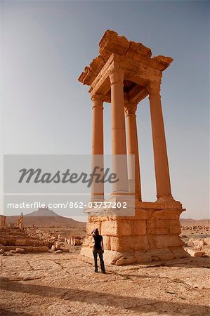 Syria, Palmyra. A tourist  stands amongst the ancient ruins of Queen Zenobia's city at Palmyra.