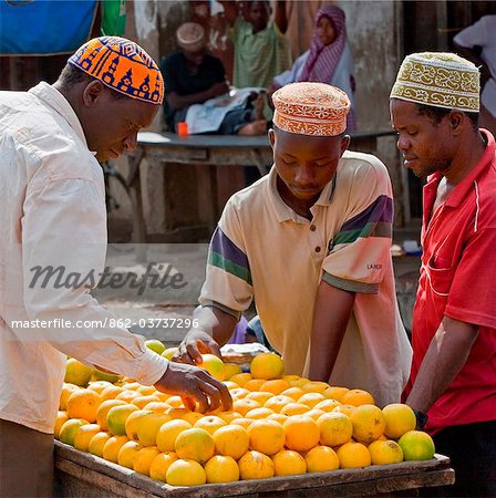 Tanzania, Zanzibar. Shoppers select locally-grown oranges from a stall at Mkokotoni Market in the northwest of Zanzibar Island.