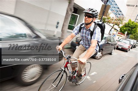 Man Riding Bicycle through Urban Traffic, San Diego, California Man Riding Bicycle through Urban Traffic, San Diego, California