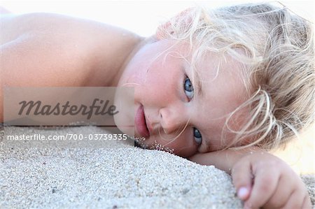 Kleines Mädchen auf Sand liegend