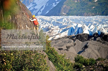 Woman rock climbing with Spencer Glacier in the background, Chugach National Forest, Kenai Peninsula, Southcentral Alaska, Summer