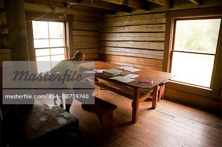 A visitor writes in a log inside the historical Slaven's Roadhouse along the the Yukon River, Yukon-Charley Rivers National Preserve, Interior Alaska, Summer