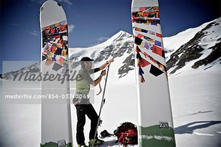 Backcountry skier prepares skis for descent of the north side of Mt. Chamberlin, Brooks Range, ANWR, Arctic Alaska, Summer