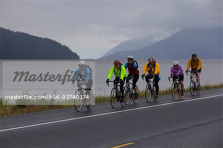 A group of bikers ride on the shoulder of the Seward Highway just south of Girdwood during a rainy weekend race, Southcentral Alaska, Summer