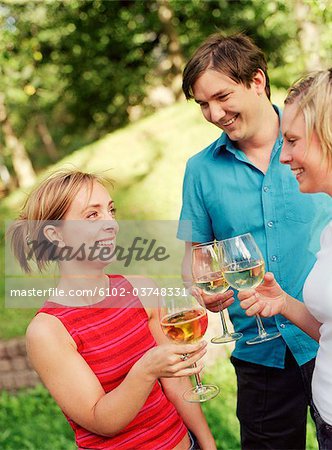 Three people toasting in a garden.