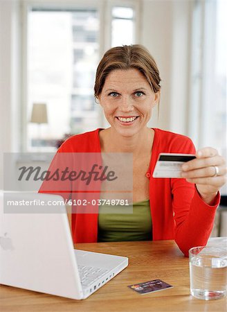 A woman with a credit card by a computer.