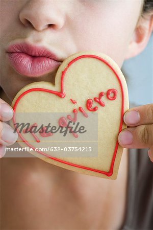 Femme plissement des lèvres, tenant des biscuits en forme de coeur